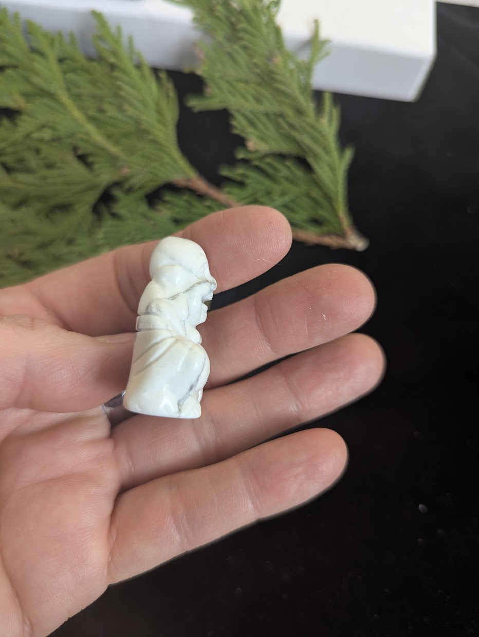 Side profile of a hand-held Howlite Laughing Buddha totem.