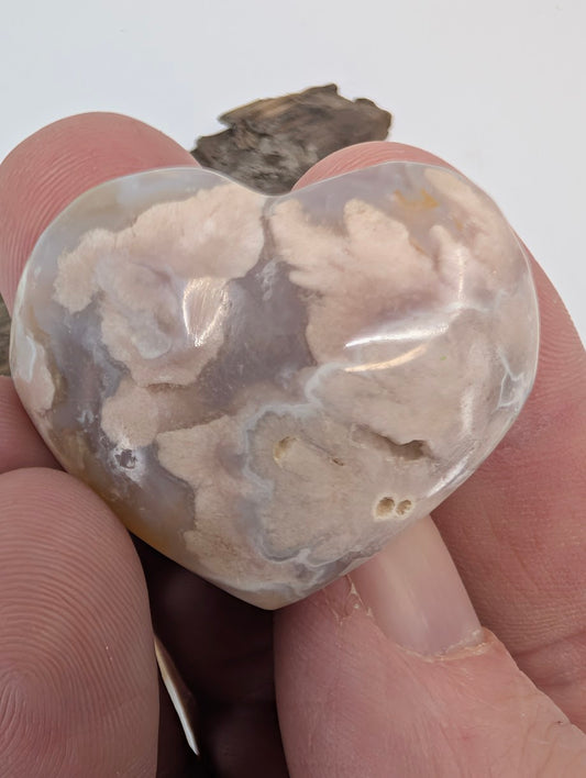 Fingers holding a small 25g Flower Agate heart to show petite size.