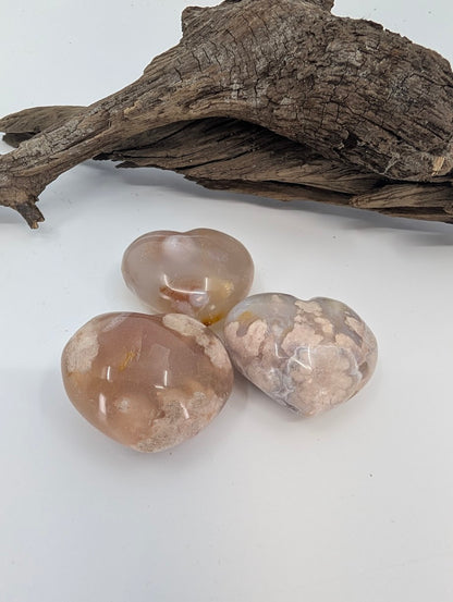 Trio of small Flower Agate hearts showing pink translucency.
