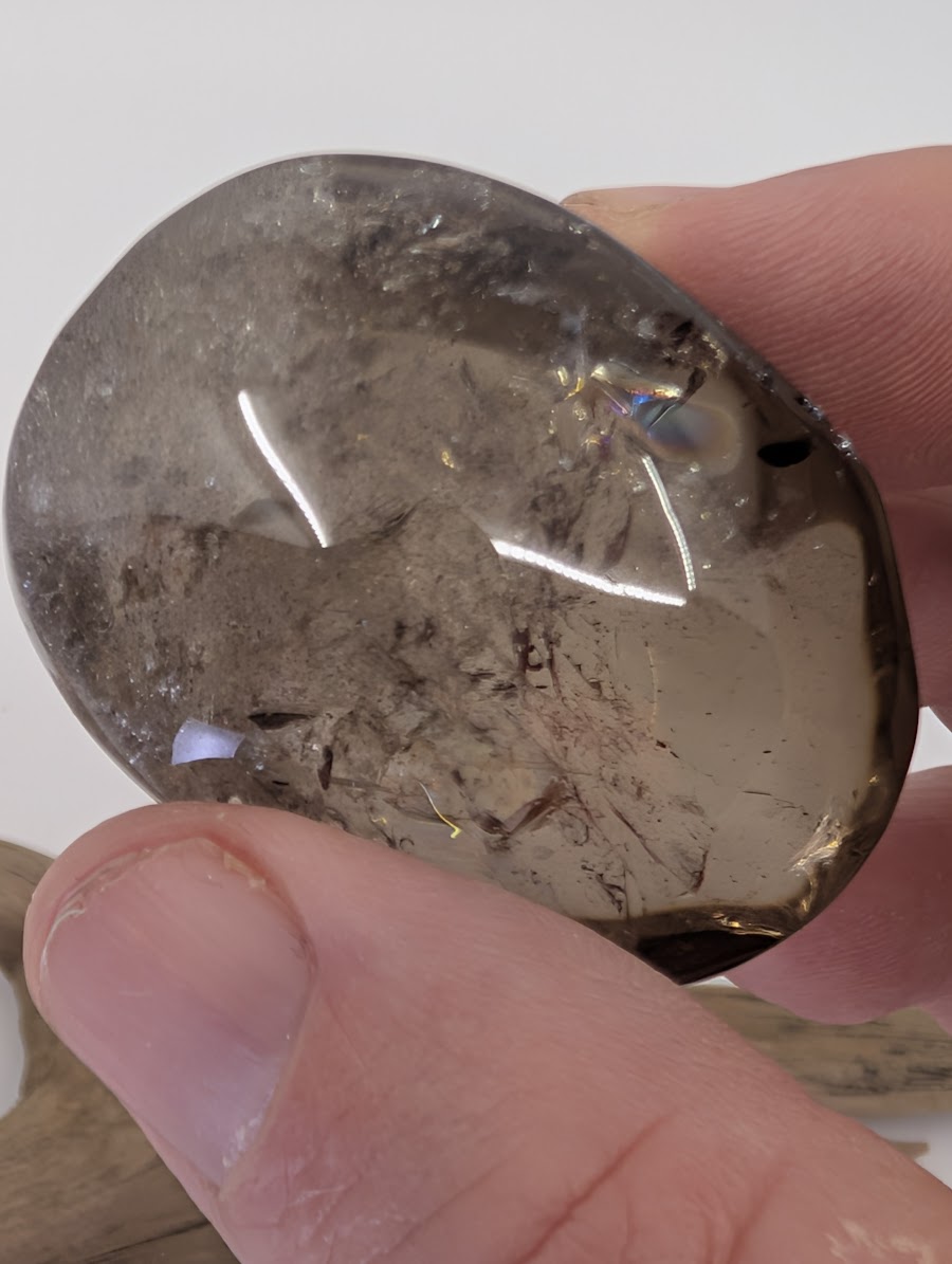 Close-up of a medium Lwena Citrine palm stone showing internal rainbow prisms and natural veils.
