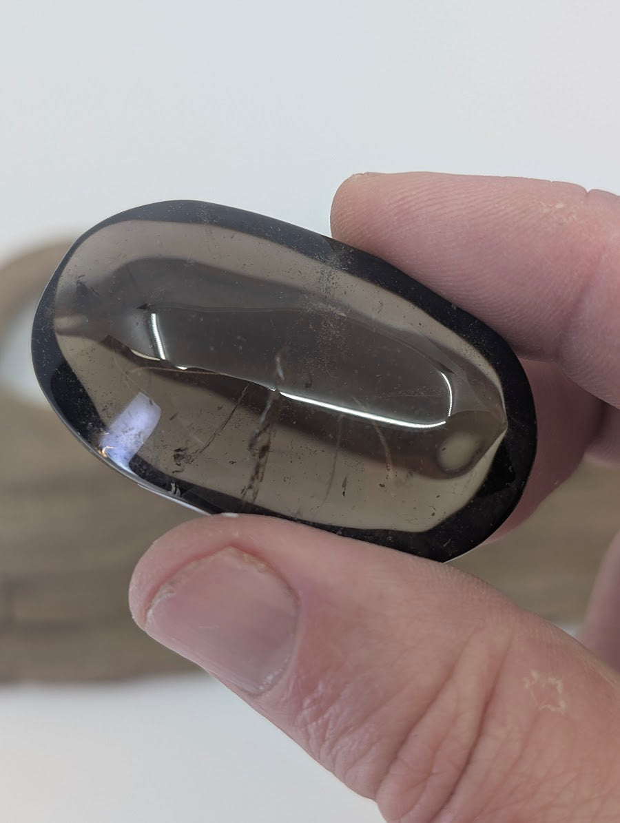 Side-profile view of a polished Smokey Citrine palm stone showing professional luster and thickness.