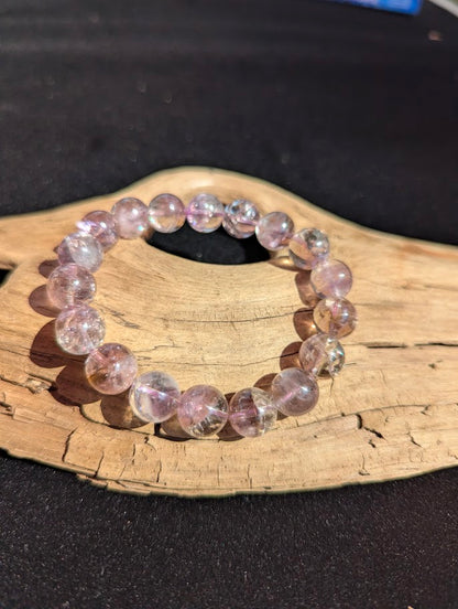 Intuitively selected 11mm AA Grade Smoky Amethyst beaded stretch bracelet displayed on driftwood, showing bi-colour quartz tones.