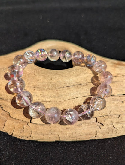 Intuitively selected 12mm AA Grade Smoky Amethyst beaded stretch bracelet resting on a driftwood display.