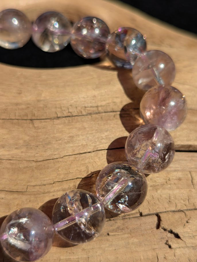 Macro detail of 12mm Smoky Amethyst round beads highlighting vivid rainbow refraction within the quartz crystal.