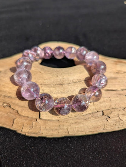 Intuitively selected 13mm AA Grade Smoky Amethyst beaded stretch bracelet on driftwood, showing large translucent spherical beads.