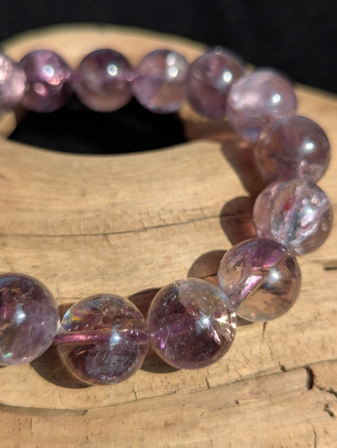 Macro close-up of 13mm Smoky Amethyst beads displaying high translucency and internal rainbow fractures.