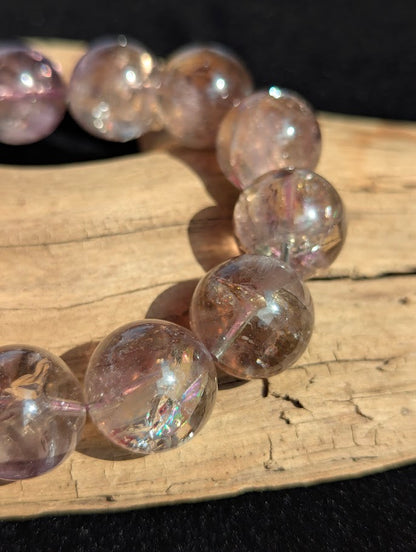 Intuitively selected 18mm statement AA Grade Smoky Amethyst beaded stretch bracelet resting on driftwood, showcasing large collector spheres.