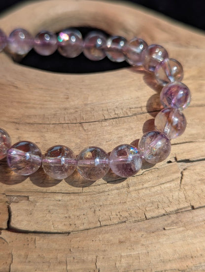 Macro photograph of 8mm Smoky Amethyst quartz beads highlighting natural internal rainbow flashes and high glassy lustre.
