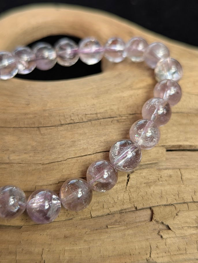 Macro view of 9mm polished Smoky Amethyst beads showing smoky champagne and lilac colour zoning with internal reflective planes.