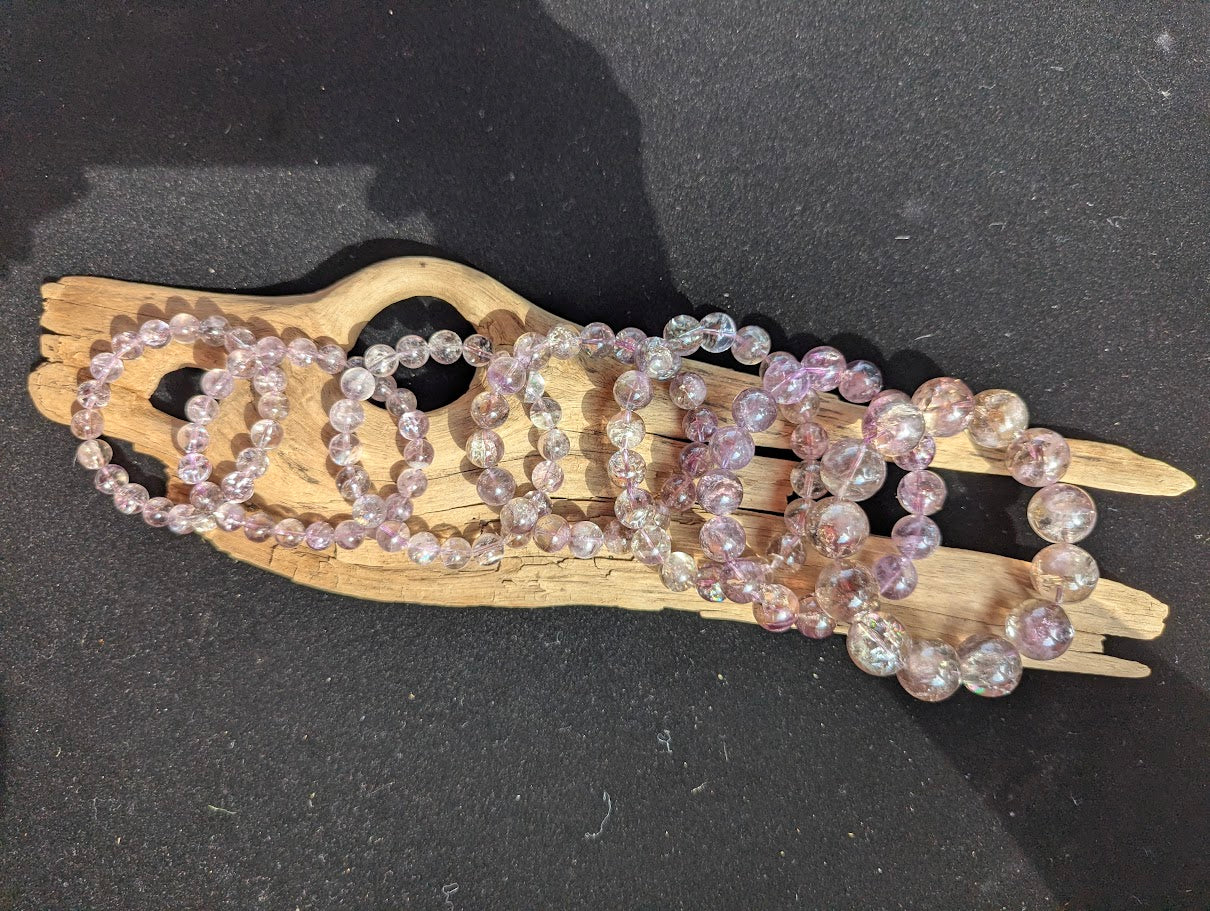 Suite of intuitively selected AA Grade Smoky Amethyst beaded bracelets displayed side-by-side on driftwood showing sizes 8mm through 18mm.