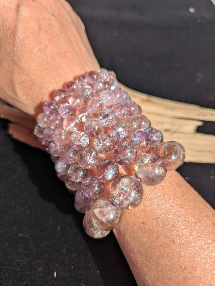 Stack of intuitively selected AA Grade Smoky Amethyst beaded bracelets worn together on a wrist demonstrating size progression from 8mm to 18mm.