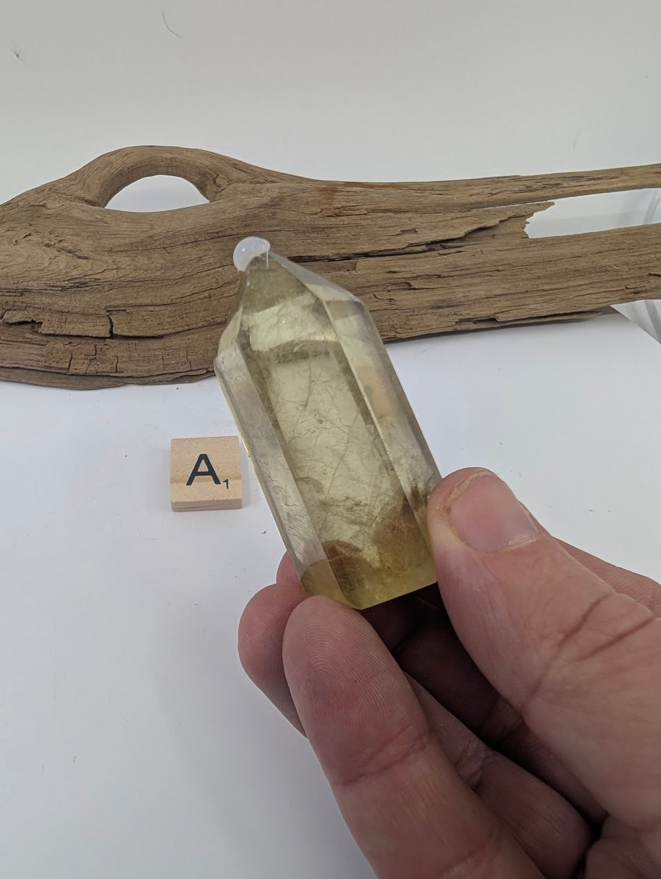 Hand holding Piece A, a 62mm polished Smoky Citrine tower from Brazil with light golden tones.