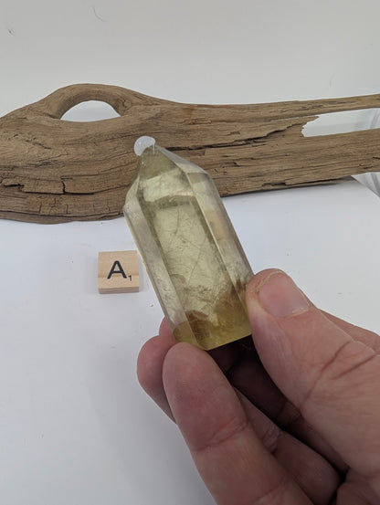 Hand holding Piece A, a 62mm polished Smoky Citrine tower from Brazil with light golden tones.