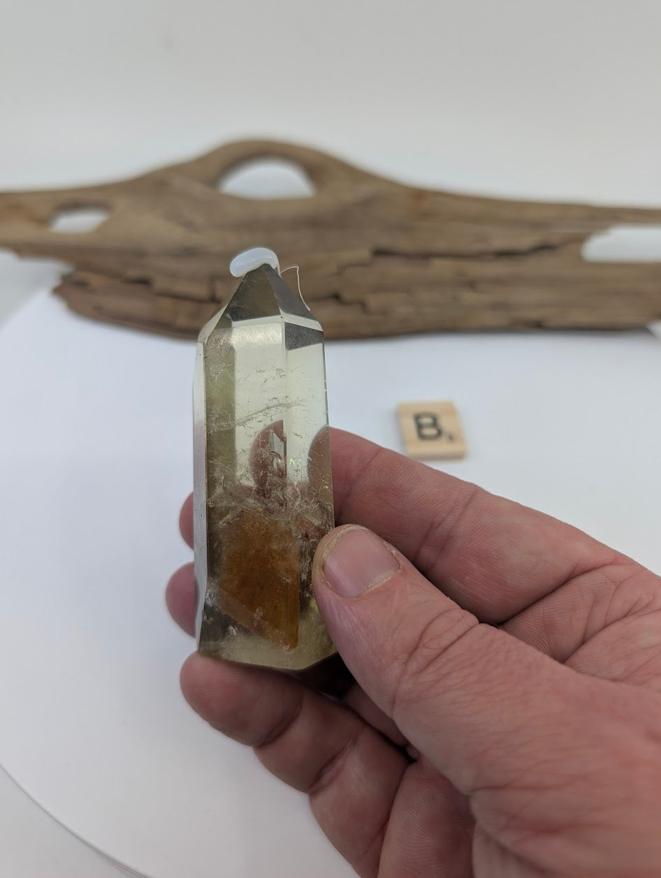 Hand holding Piece B, a 78mm polished Smoky Citrine tower from Brazil with a dark phantom zone.