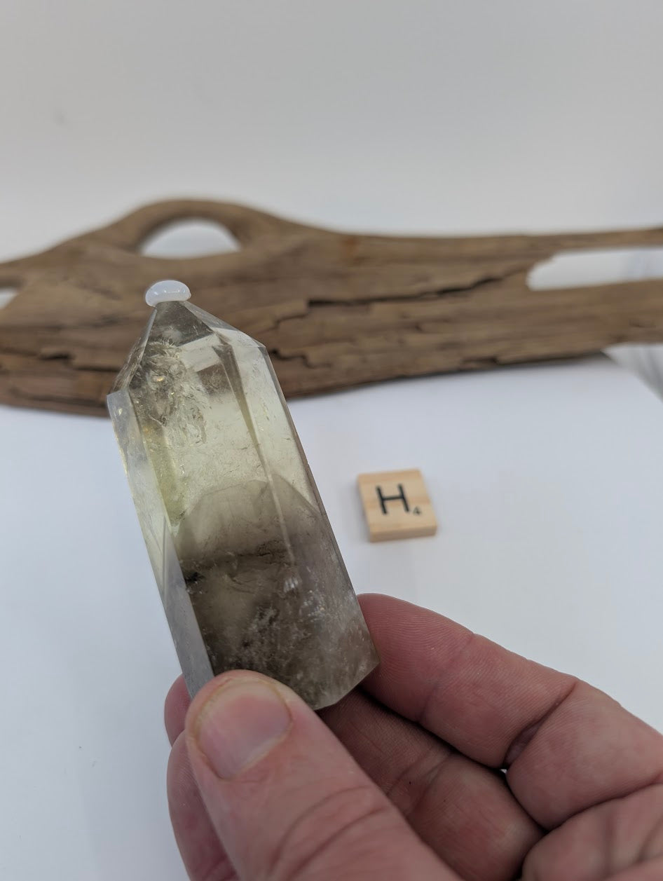 Hand holding Piece H, an 80mm polished Smoky Citrine tower from Brazil with deep grounding tones.