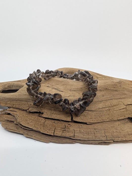 Smoky quartz chip bracelet with translucent smoke-grey chips displayed on driftwood