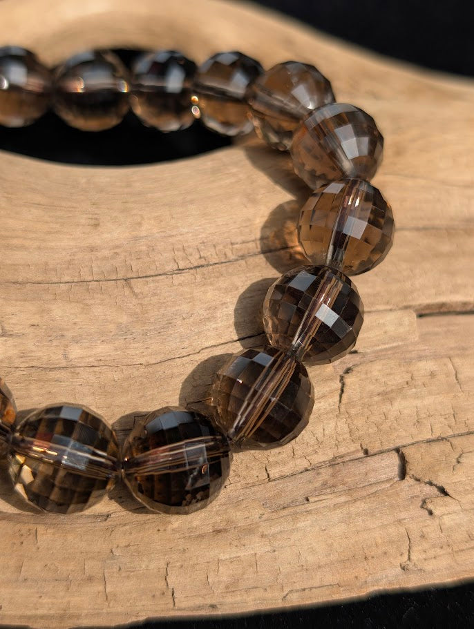 Macro close-up of 12mm faceted Smoky Quartz beads highlighting the geometric surface cuts and light refraction.