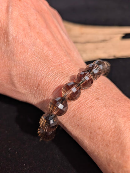12mm faceted Smoky Quartz beaded stretch bracelet worn on a wrist for size scale.