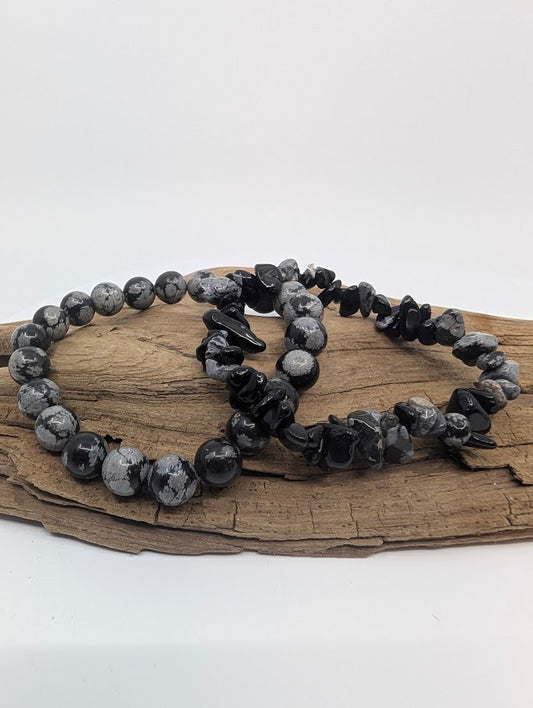 Snowflake Obsidian 8MM and chip bracelets displayed on wood