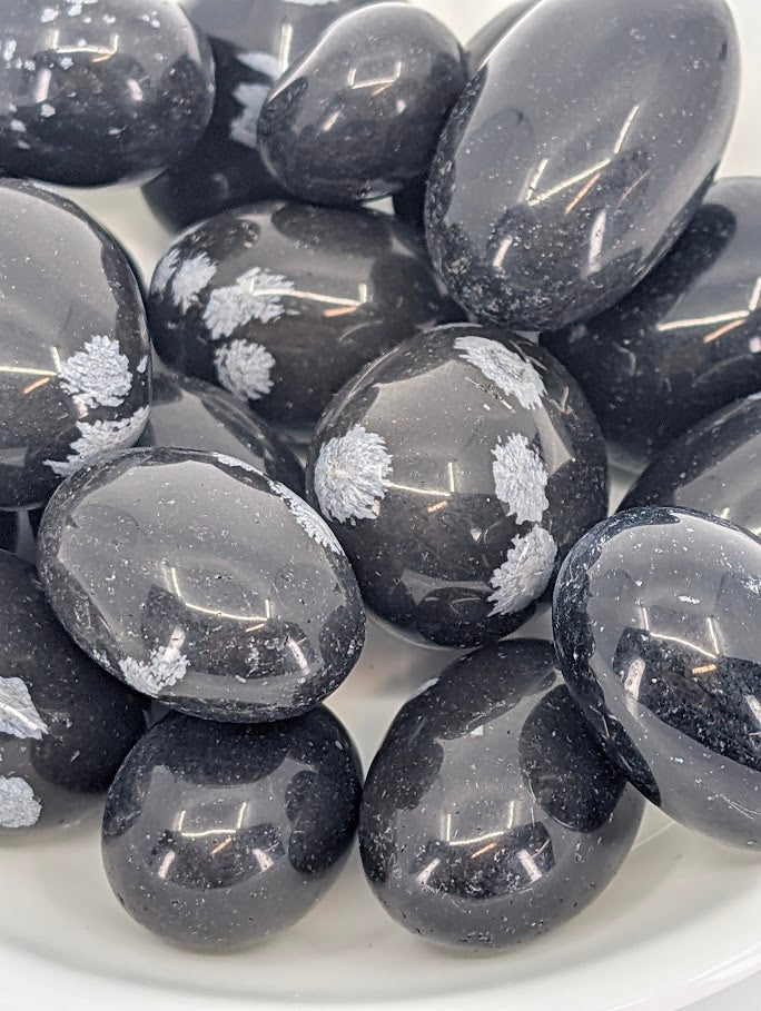 Close-up of Snowflake Obsidian tumbled stones showing gray snowflake inclusions