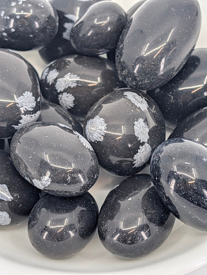 Close-up of Snowflake Obsidian tumbled stones showing gray snowflake inclusions