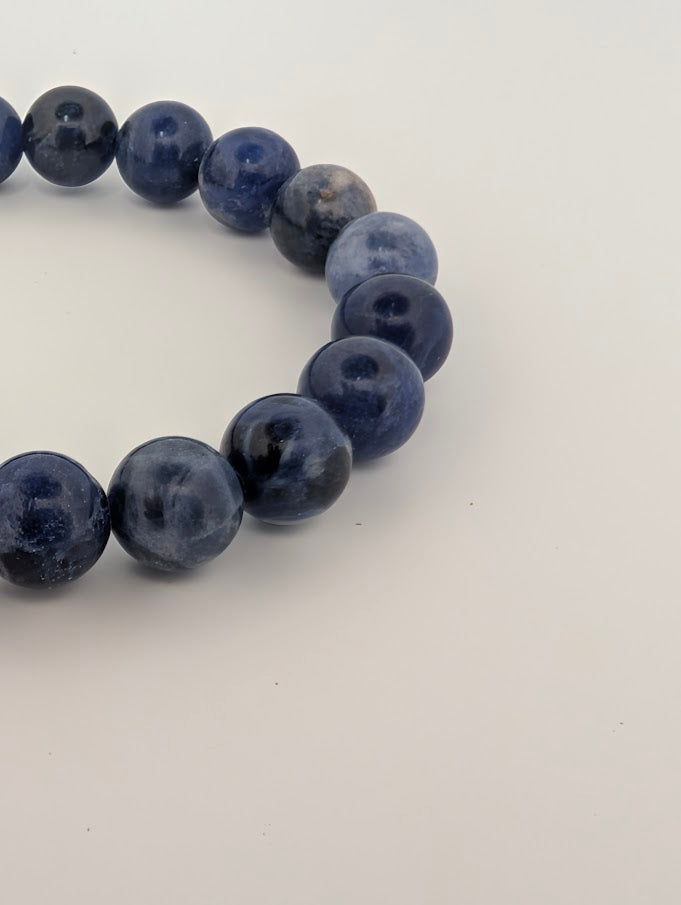 Detail of polished 8MM sodalite bracelet beads with blue and white marbling
