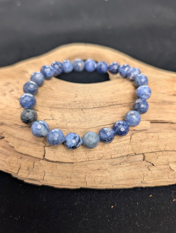 8mm faceted Sodalite beaded stretch bracelet resting on a driftwood display, showing royal blue and white colouration.