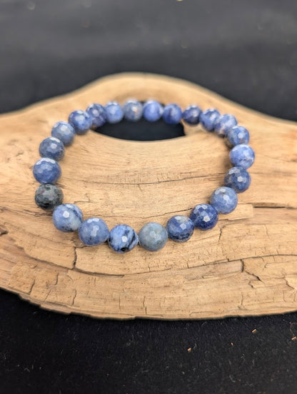 8mm faceted Sodalite beaded stretch bracelet resting on a driftwood display, showing royal blue and white colouration.