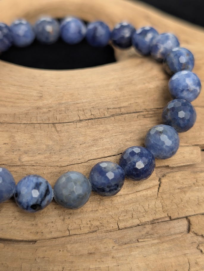 Macro close-up of 8mm faceted Sodalite beads highlighting geometric surface cuts and natural white calcite inclusions.