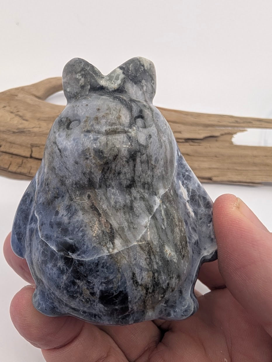 Sodalite Totoro (285g) held in hand showing the 7.5cm height and variegated mineral color.