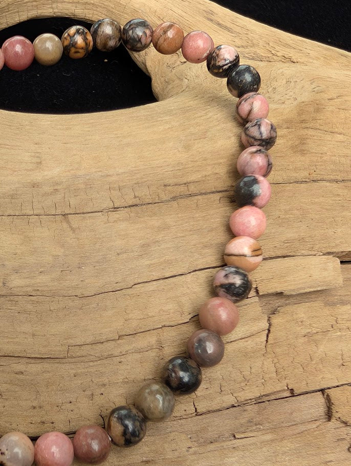 Macro close-up of 4mm polished Spider Web Rhodonite beads highlighting the high-gloss finish and natural black dendritic webbing.