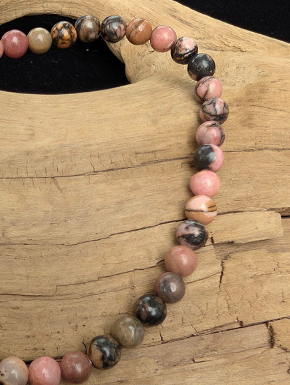 Macro close-up of 4mm polished Spider Web Rhodonite beads highlighting the high-gloss finish and natural black dendritic webbing.