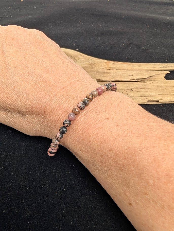 4mm polished Spider Web Rhodonite beaded stretch bracelet worn on a wrist for delicate size scale.
