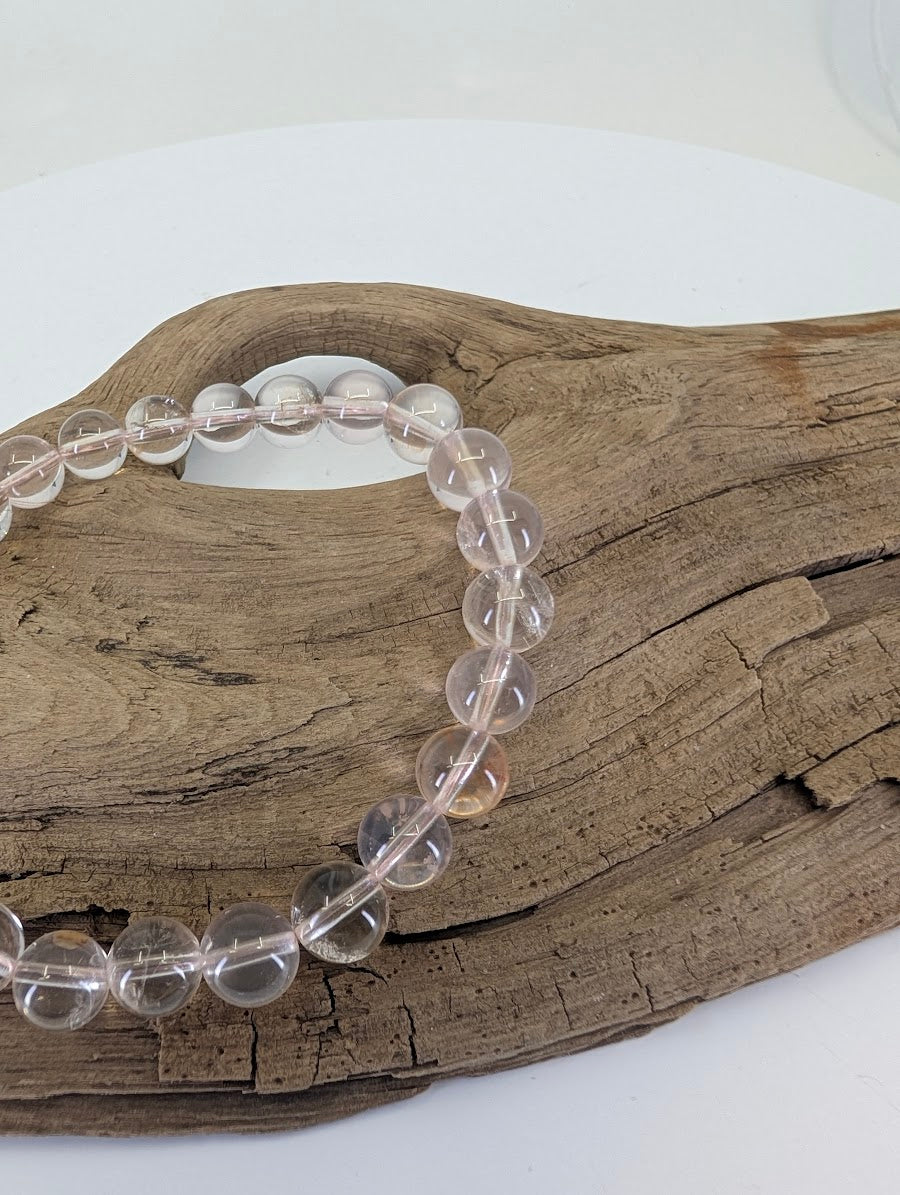 Close-up of 8mm Rose Quartz beads highlighting the internal "whisper-pink" veils and silky textures.
