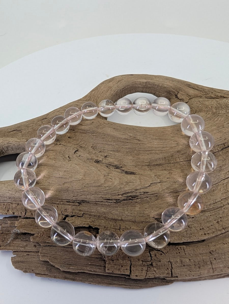 8mm Star Flash Rose Quartz bead bracelet from Brazil showing high-clarity watery pink tones on wood.