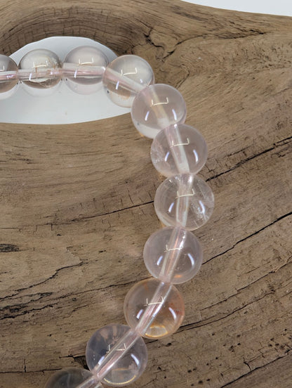 Macro view of Brazilian Rose Quartz beads showing professional high-gloss polish and authentic light-play.