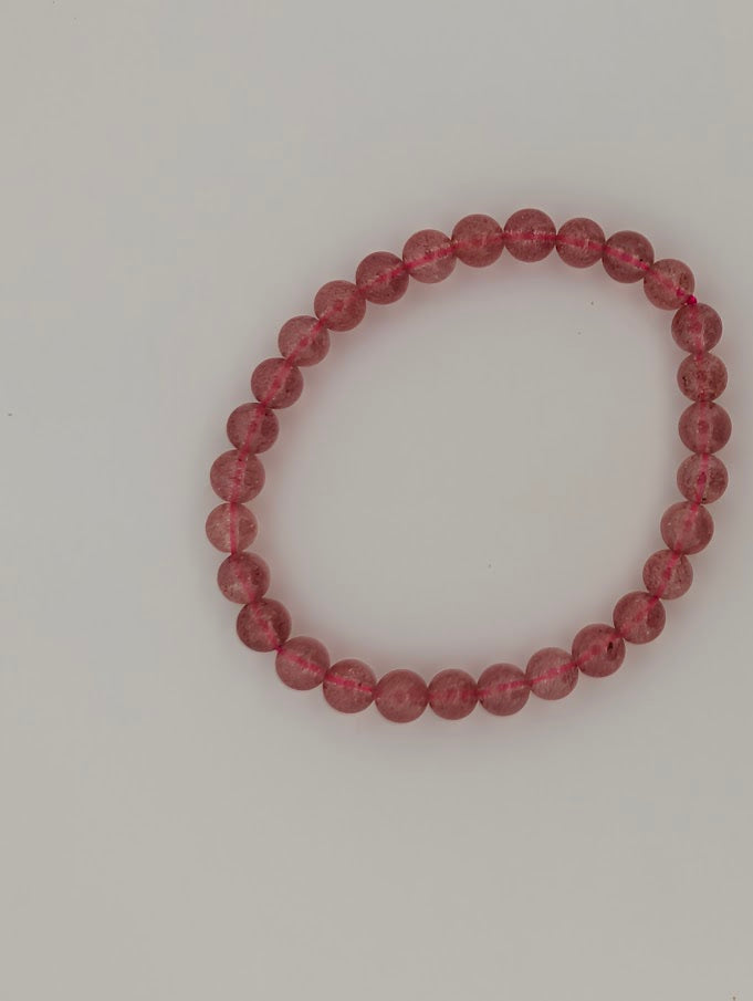 Top-down view of 6mm Strawberry Quartz bracelet on white background