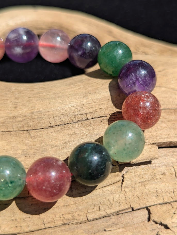 Macro close-up of 11mm polished Super 8 beads highlighting the natural inclusions and diverse mineral palette of amethyst, aventurine, and strawberry quartz.