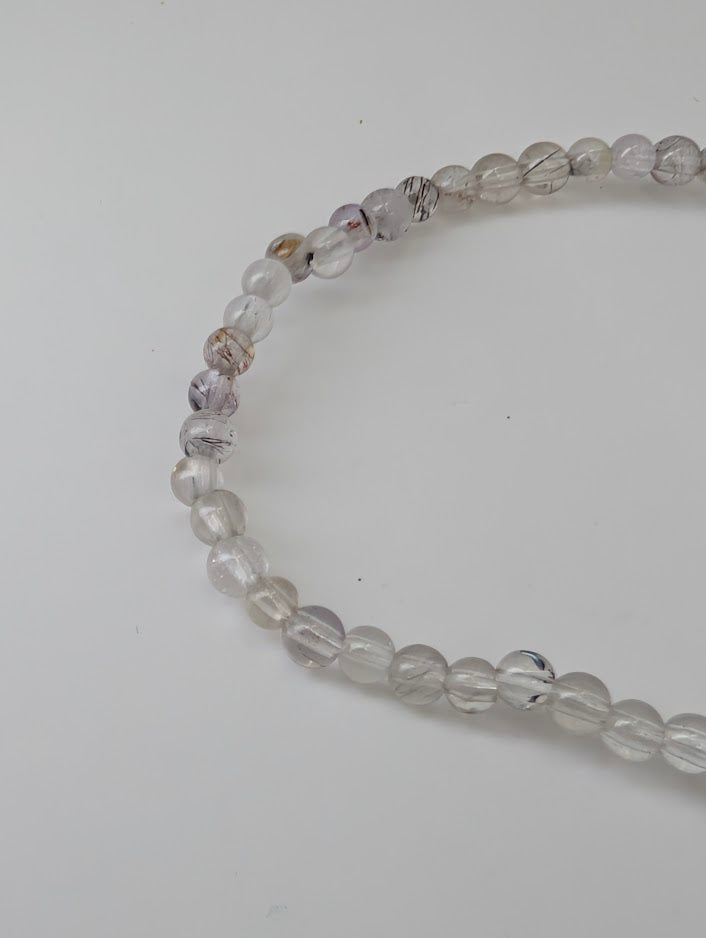 Detailed view of 3 mm Super Seven beads with rutile and hematite inclusions