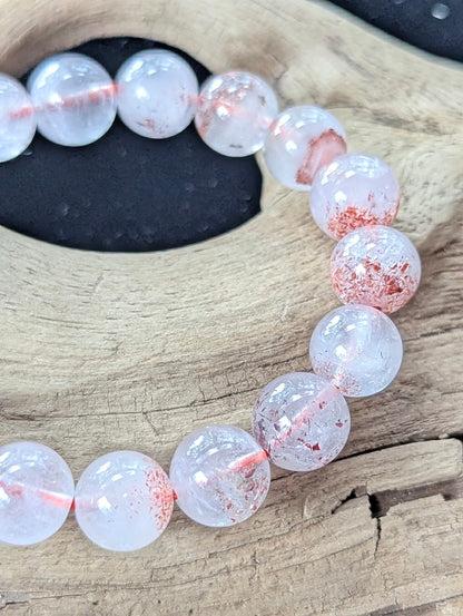 Close-up macro view of 10mm Super Seven beads displaying exceptional transparency and suspended orange-red needles.
