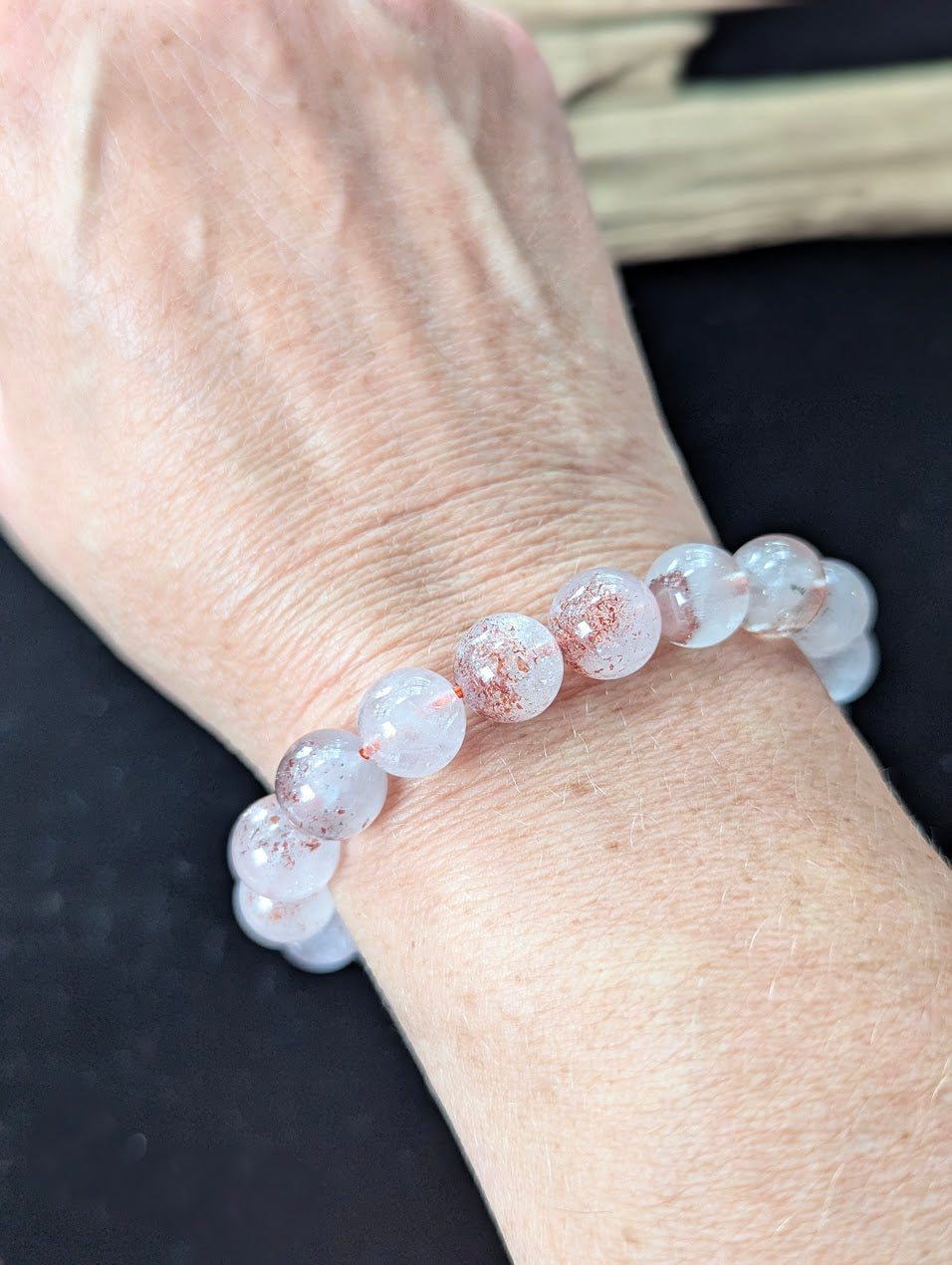 Prominent 10mm Super Seven beaded bracelet worn on a wrist, offering a bold display of natural inclusions.