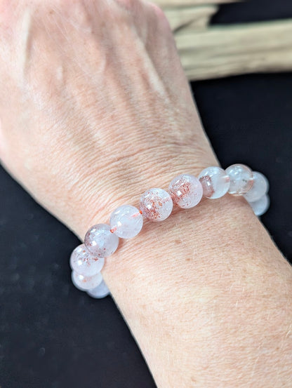 Prominent 10mm Super Seven beaded bracelet worn on a wrist, offering a bold display of natural inclusions.