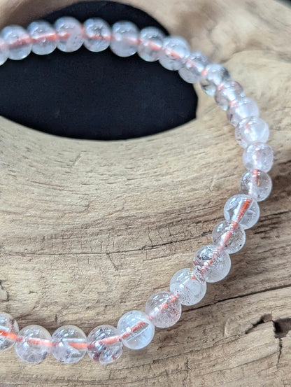 Close-up macro view of 5mm Congolese Super Seven beads highlighting their water-clear translucency and vibrant red confetti-like inclusions.