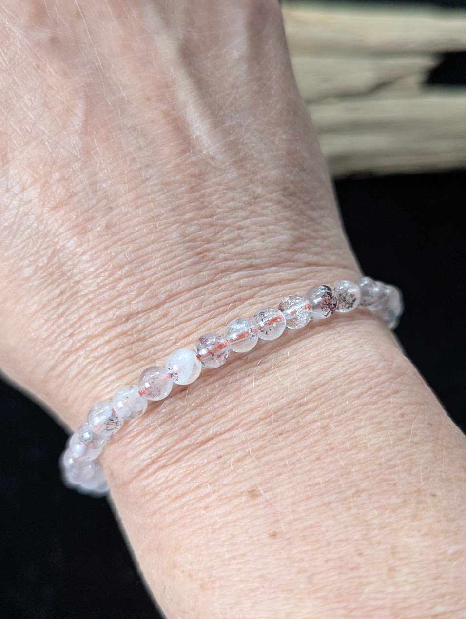 5mm Super Seven beaded bracelet worn on a wrist, demonstrating a delicate scale and clear quartz clarity.