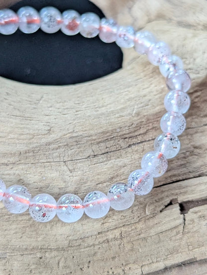 Detailed macro shot of 6mm Congolese Super Seven beads displaying pristine clarity and suspended red mineral inclusions.