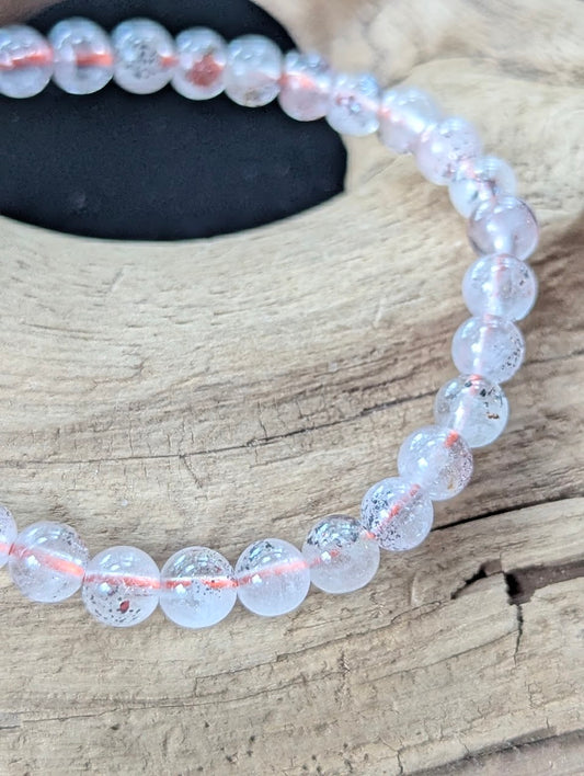 Detailed macro shot of 6mm Congolese Super Seven beads displaying pristine clarity and suspended red mineral inclusions.