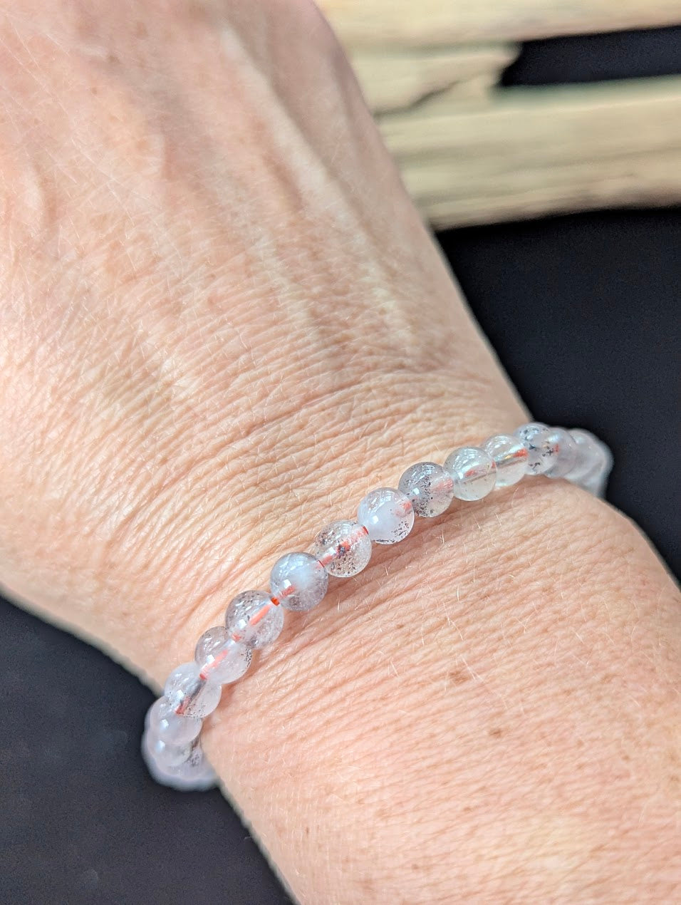 6mm Super Seven gemstone bracelet styled on a wrist, showing excellent transparency and a glassy polish.