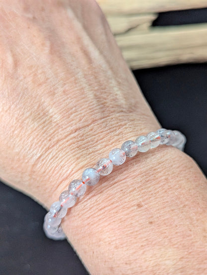 6mm Super Seven gemstone bracelet styled on a wrist, showing excellent transparency and a glassy polish.