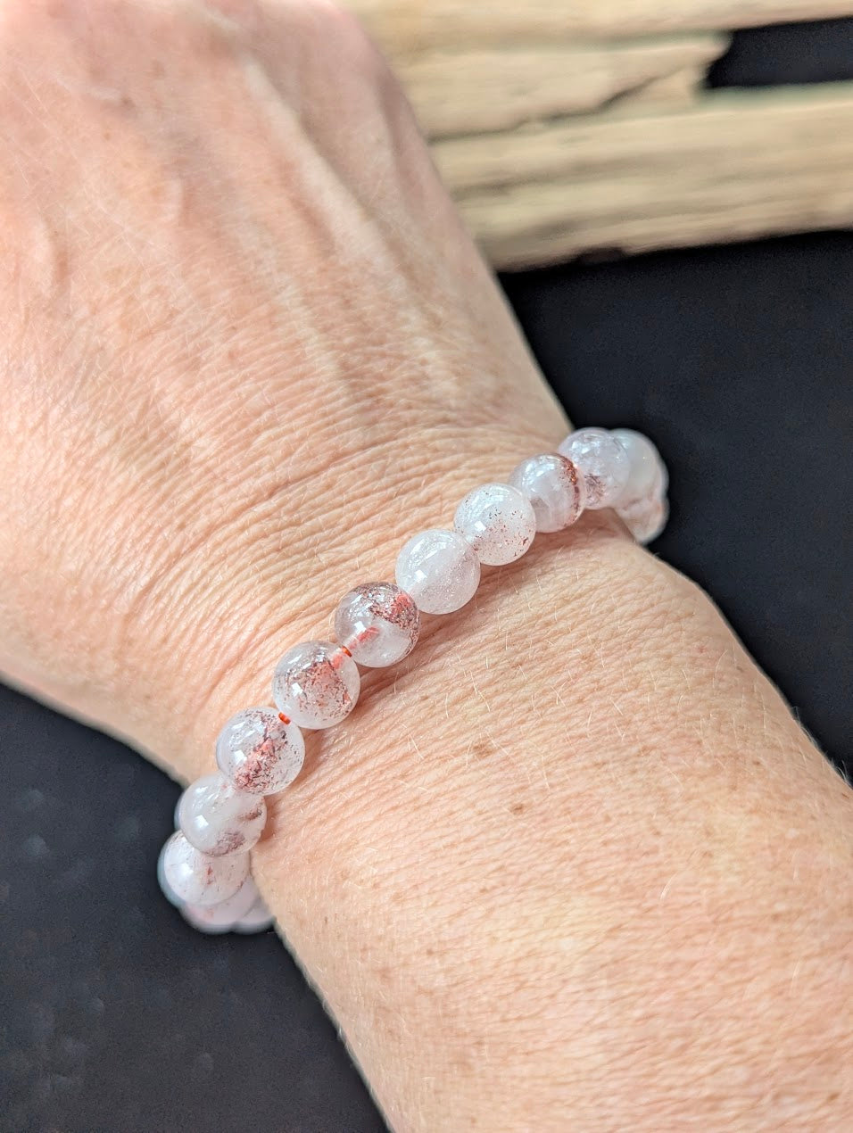 8mm Super Seven gemstone bracelet styled on a wrist, demonstrating size and glowing clarity.