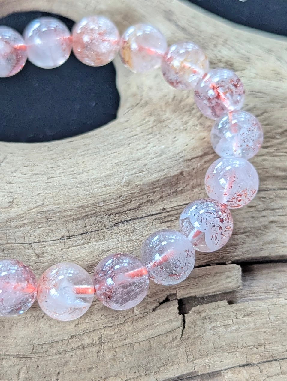 Detailed macro shot of 9mm Congolese Super Seven beads displaying pristine polish and rich hematoid flakes.